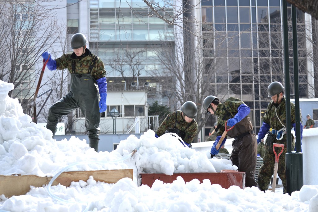 Members of the Japan Self Defense Forces work near a large snow sculpture they are building. 